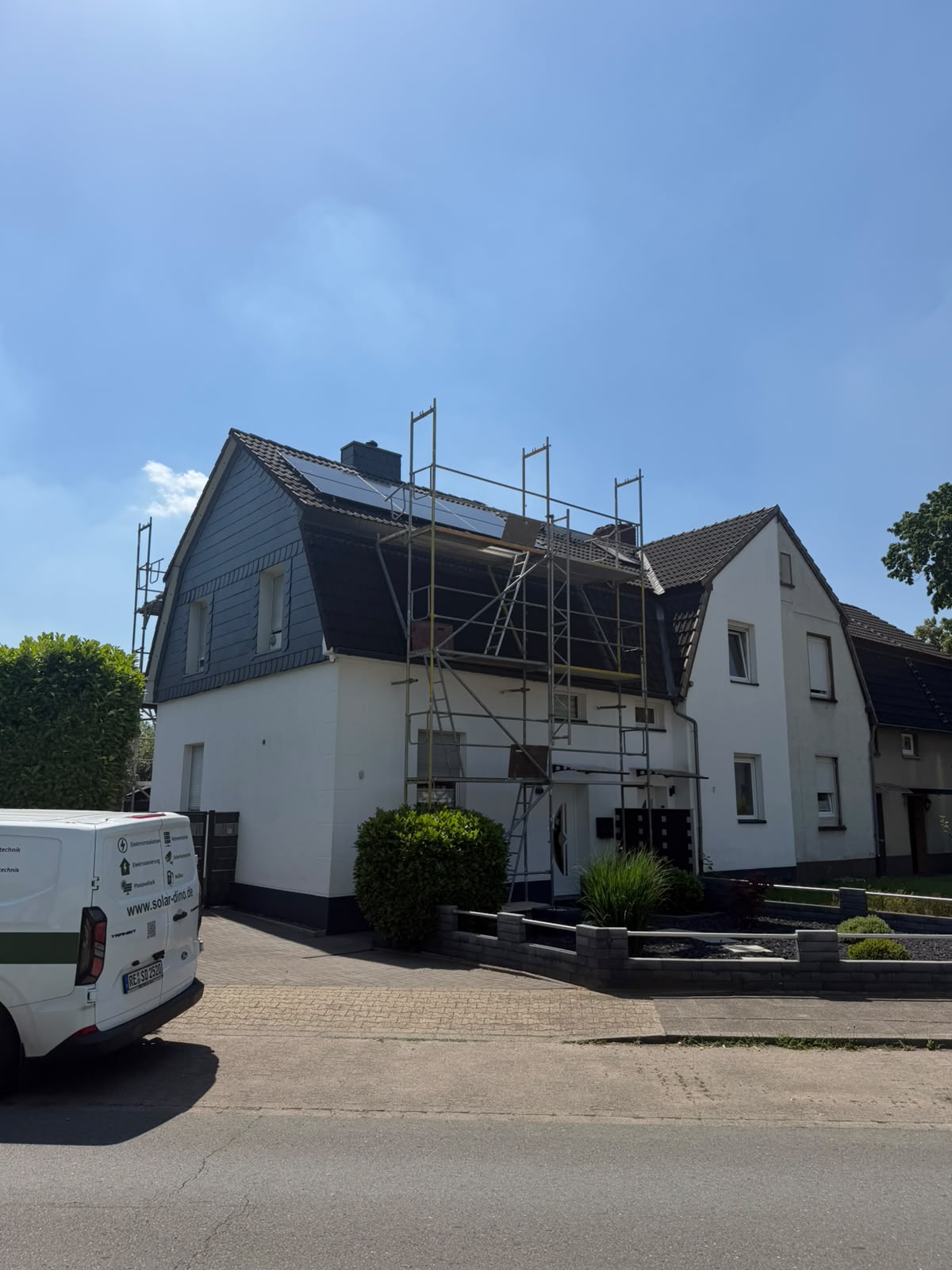Wohnhaus mit Photovoltaikmodulen, Gerüst und Solar-Dino-Firmenwagen davor